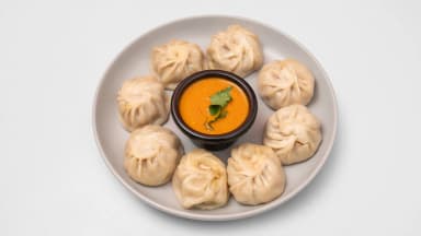 Chicken steamed momo dumplings with tomato achar dip on a plate at Taste of Himalayan, Rowley Regis