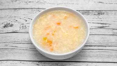 Chicken sweetcorn soup in a white bowl on a wooden table